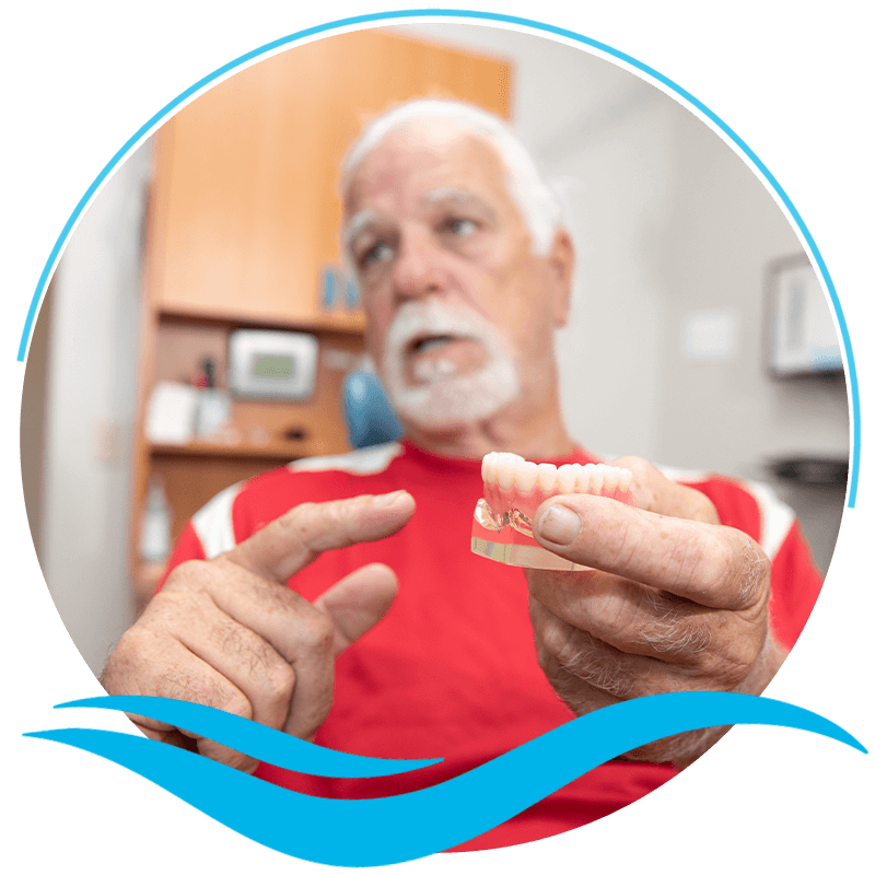 Patient pointing at a model of full arch dental implants