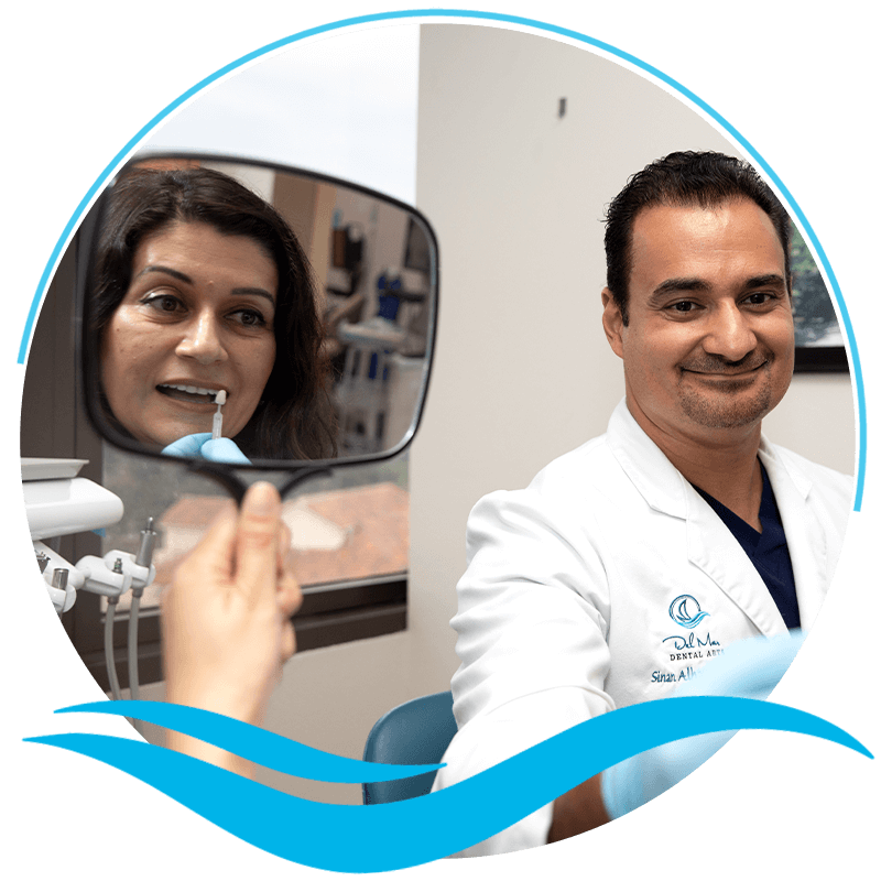 Doctor holding up veneers to Patient Mouth